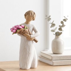 Willow Tree Bright Hope figur, der holder en buket lyser�de blomster. Figuren st�r smukt p� en lys tr�kommode og er en bet�nksom gaveid�.